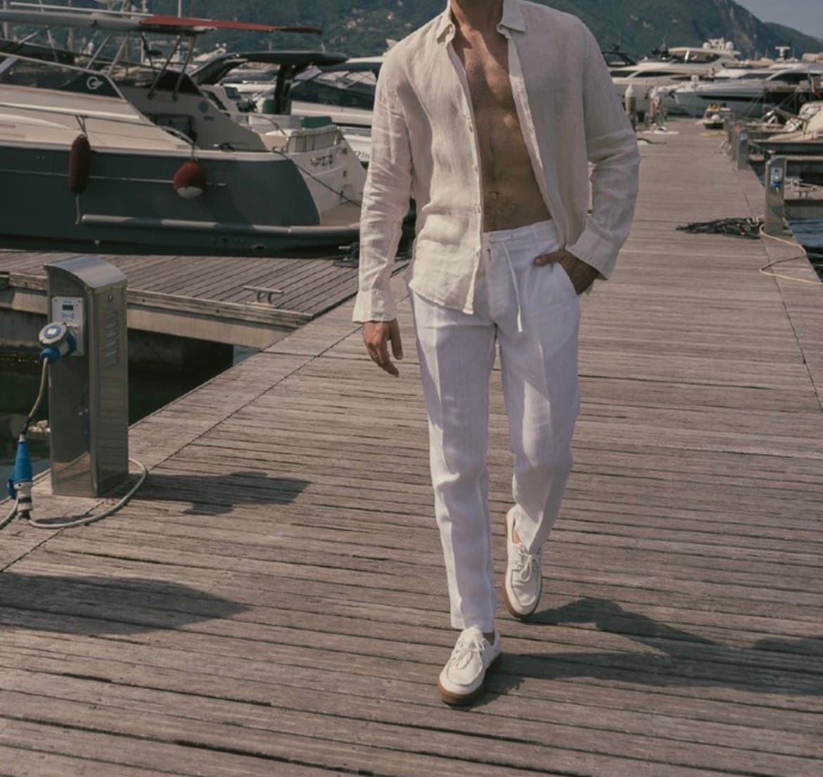 Modello indossa pantaloni in lino bianco su un pontile