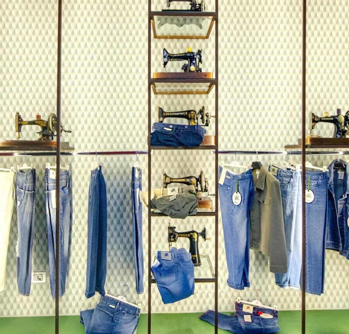 Macchine da cucire d'epoca e capi in denim esposti nell'atelier