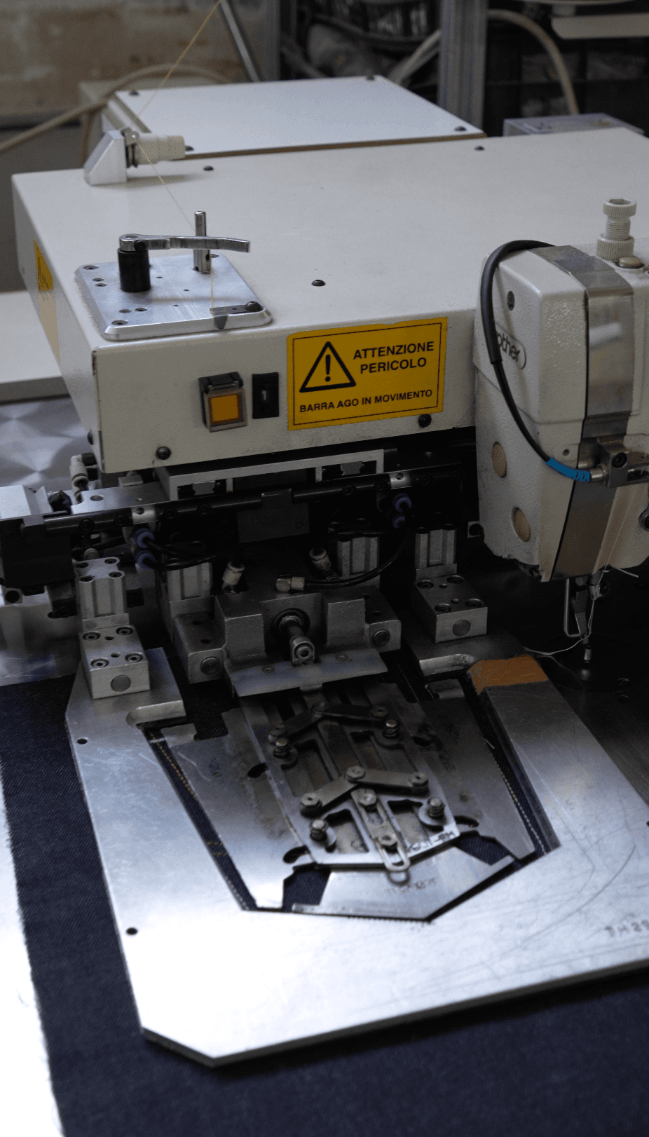 Macchina da cucire industriale con rocchetti di filo nel reparto confezione
